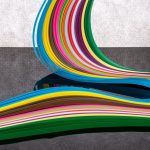 Curving bands of colored paper strips running from one color to the next, an abstract nod to the pH color scale