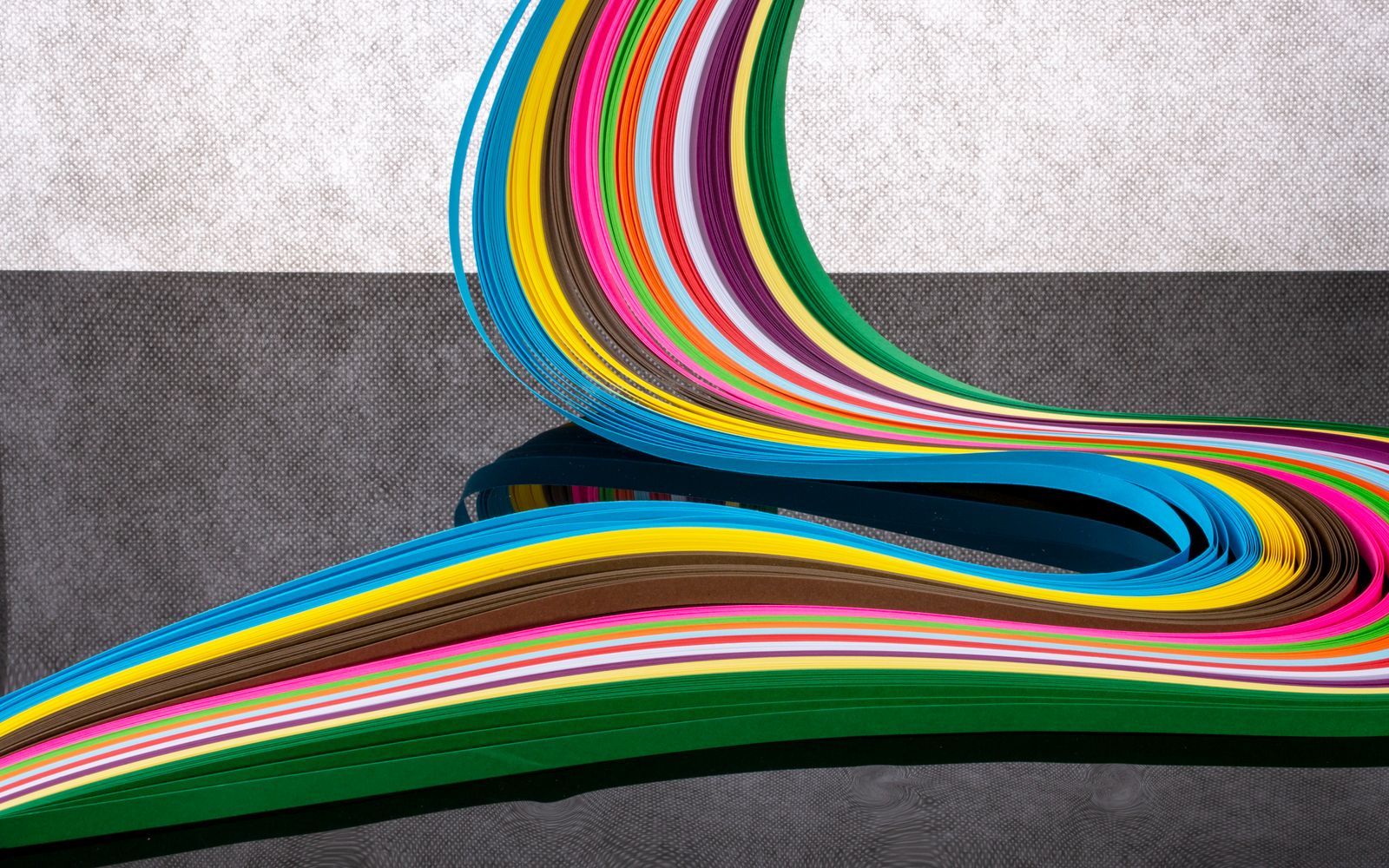 Curving bands of colored paper strips running from one color to the next, an abstract nod to the pH color scale