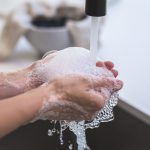 Soapy hands being rinsed under a running tap