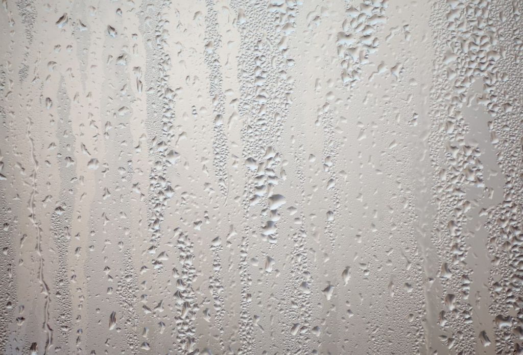 Condensation droplets running down a steamed glass surface